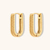 Boucles d’oreilles dorées rectangulaires nervurées, posées sur fond blanc