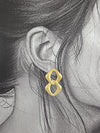 Boucle d’oreille dorée à deux maillons sculptés, vue de face, fond blanc