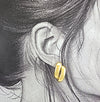 Boucle d’oreille dorée bombée à double arc, vue de face, fond blanc