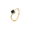Bague dorée moderne avec pierre noire graphique, posée sur fond blanc