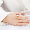 Bague dorée au design ondulé et fluide, avec une forme libre et moderne, présentée sur fond blanc