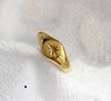 Bague style signet dorée avec étoile gravée au centre, finition lisse et brillante