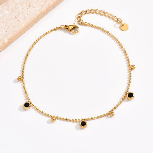 Bracelet doré fin pour femme, orné de petites pampilles noires brillantes. Modèle Noir Minuit signé Alberto Bijoux, un bijou chic et mystérieux au charme discret.