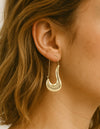 Boucles d’oreilles pendantes dorées avec design sculptural incurvé en acier inoxydable. alberto bijouterie montreal 