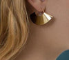 Boucles d’oreilles dorées en forme d’éventail portées sur une oreille, finition brillante