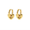 Boucles d’oreilles dorées en forme de cœur bombé avec anneau épais, portées à l’oreille.