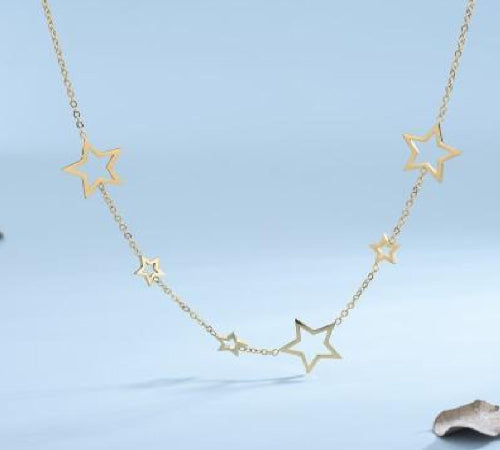 Collier doré avec étoiles ajourées de différentes tailles, sur fond bleu pastel.