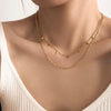 Collier doré à deux rangs avec petits pendentifs carrés, style délicat et moderne, présenté sur fond blanc