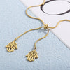 Collier doré avec deux pendentifs hamsa superposés, symbole protecteur, présenté sur fond blanc