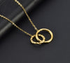 Collier doré avec deux anneaux entrelacés, l’un lisse et l’autre torsadé, posé sur fond noir.