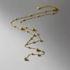 Collier en Y doré avec petites pampilles arrondies suspendues sur une chaîne fine, présenté sur fond blanc
