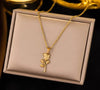 Collier doré avec pendentif en forme de rose, présenté sur coussin beige.