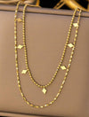 Long collier doré à l’or 18k avec maillons perlés et motifs losanges plats, présenté en double tour.