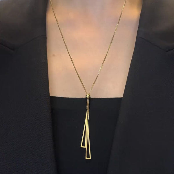 Collier doré 18k avec double pendentif triangle ajouré suspendu à une chaîne fine avec bille centrale.