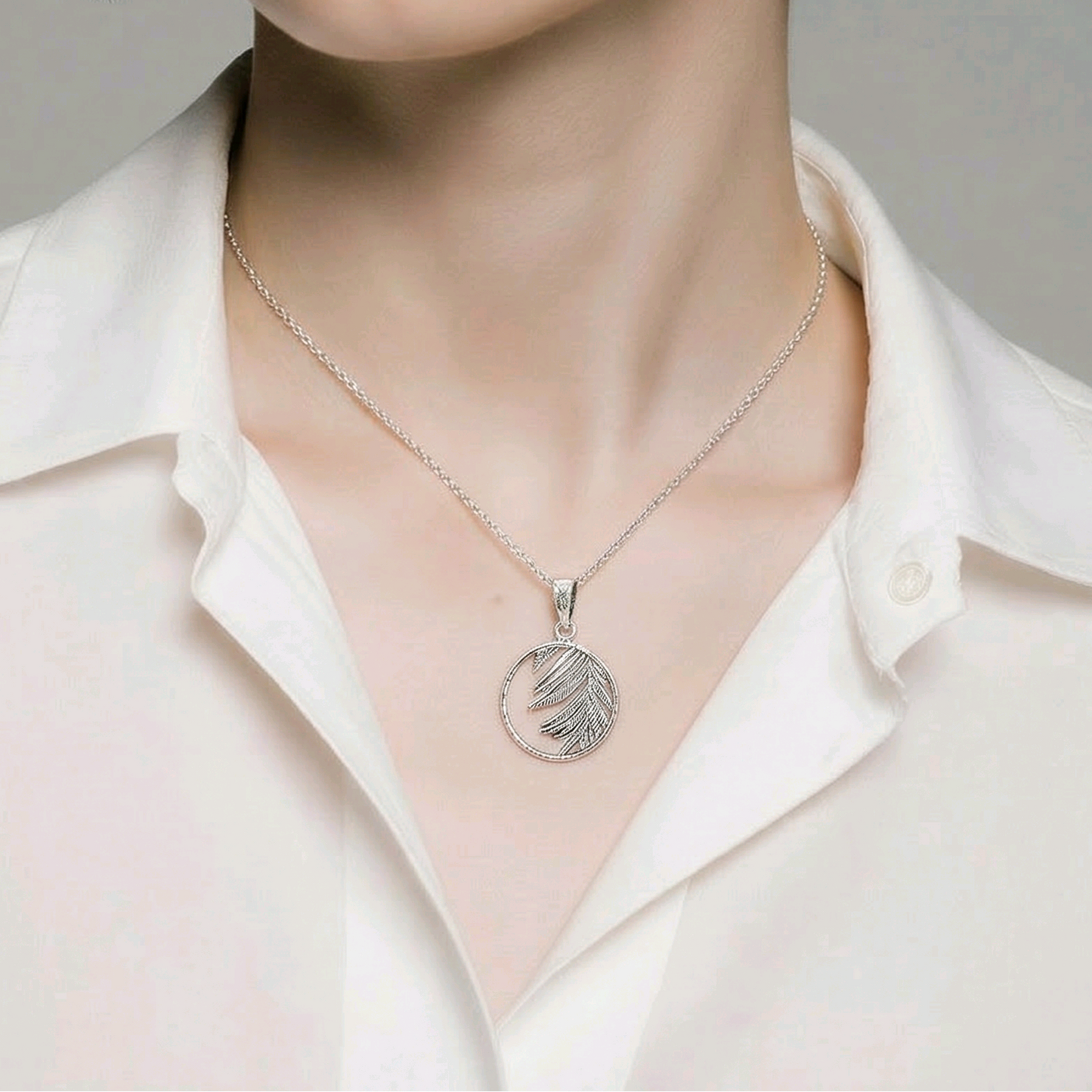Pendentif rond ajouré en argent sterling 925 oxydé avec feuille de palmier gravée en relief débordant du cercle, 17mm, fond blanc