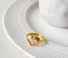 Bague dorée en forme de cœur ajouré posée sur une assiette blanche, disponible en tailles 6 à 8