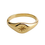 Bague signet dorée avec motif étoile du nord gravé, au style raffiné, présentée sur fond blanc